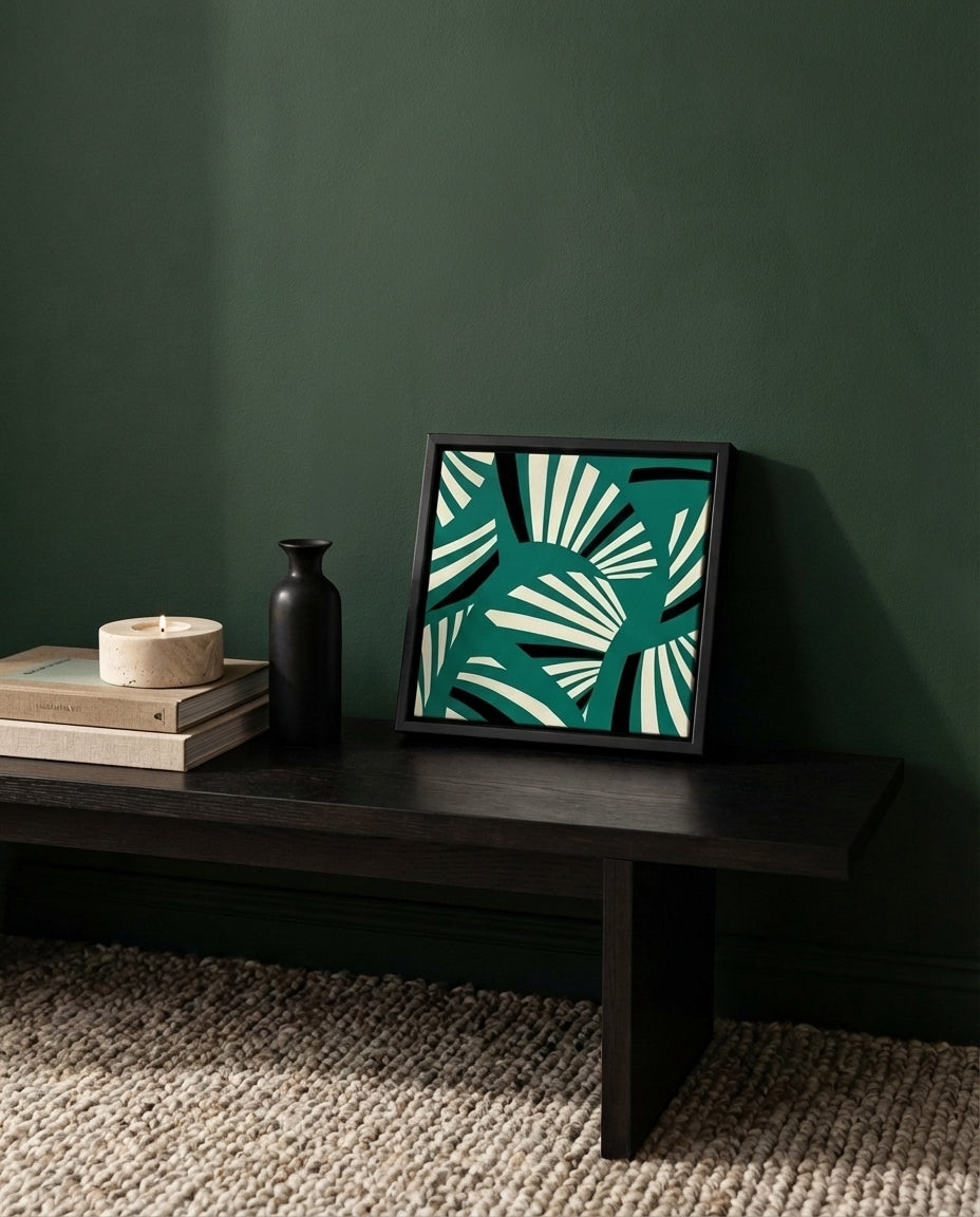 Framed red and white art deco  abstract art piece on a dark wooden table against a green wall.