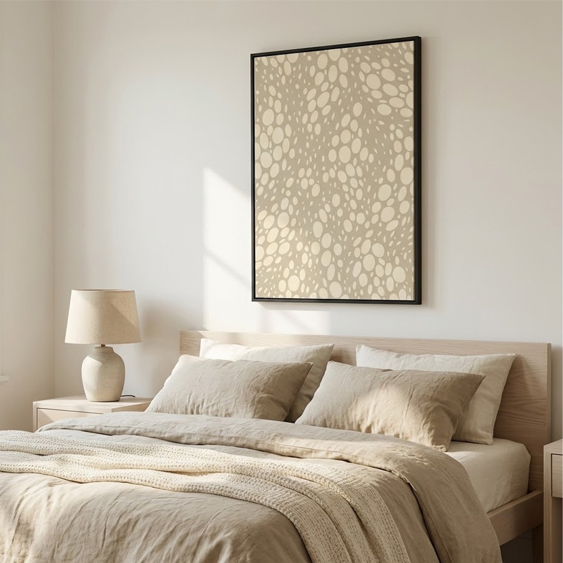Neatly made bed with beige bedding and pillows, lamp on nightstand, and the Lauren Stone wall art in a bedroom.