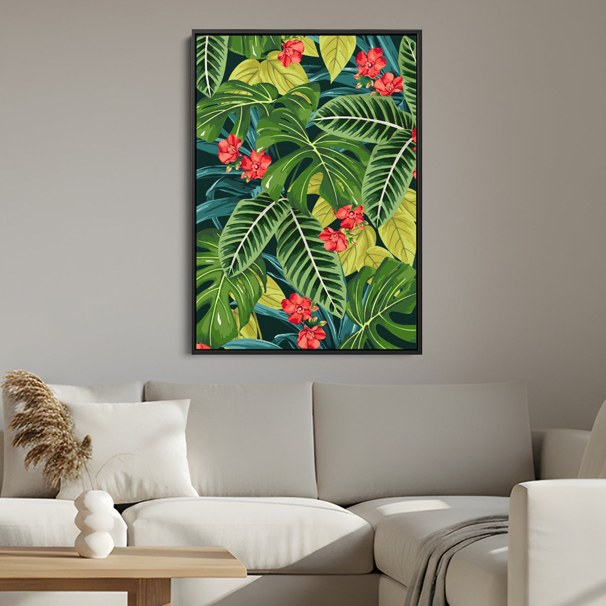 Solana scarlet canvas print in a black frame featuring a tropical leaf pattern with bright red flowers, displayed above a light beige sofa in a modern living room setting.